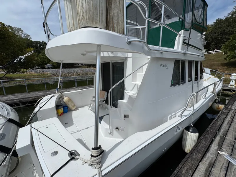 Slide: The Image of 2001 Mainship 390 yacht docked, featuring white exterior and green canopy. - 9