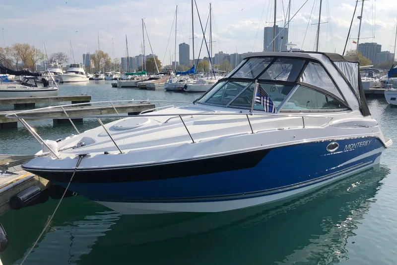 The Image of 2018 Monterey 295 Sport Yacht docked in a marina with city skyline. - 0