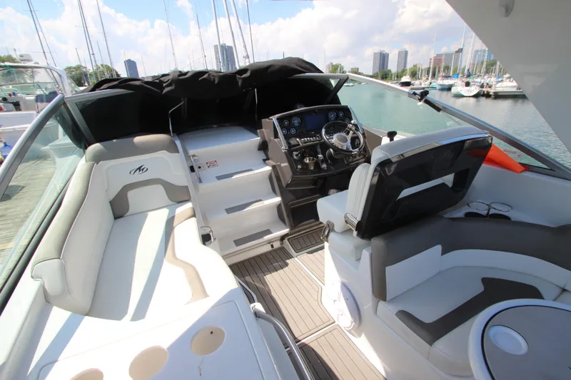 Slide: The Image of 2018 Monterey 295 Sport Yacht interior with helm, seating, and marina view. - 13