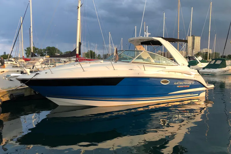 Slide: The Image of 2018 Monterey 295 Sport Yacht docked in a marina, reflecting on calm water. - 2