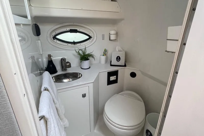 Slide: The Image of Compact bathroom in 2018 Monterey 295 Sport Yacht with sink, toilet, and porthole window. - 25
