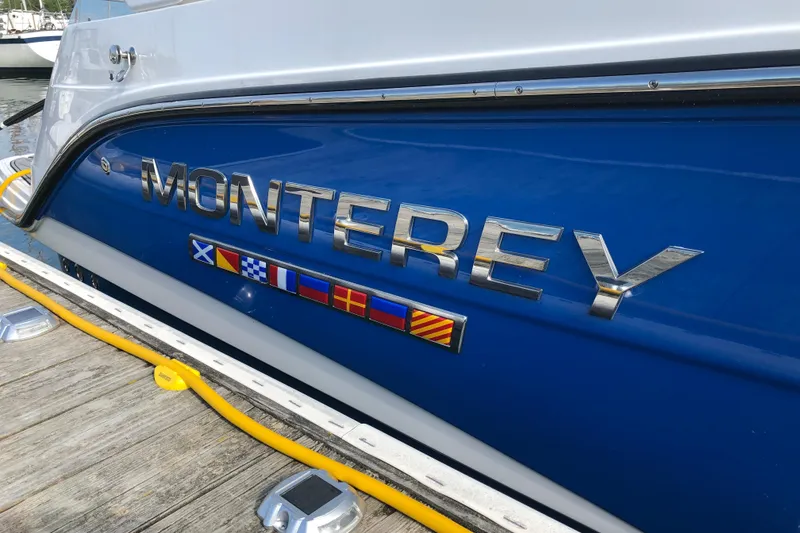 Slide: The Image of 2018 Monterey 295 Sport Yacht with nautical flags on blue hull. - 6