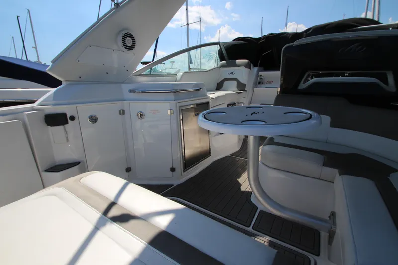 Slide: The Image of 2018 Monterey 295 Sport Yacht interior with seating, table, and cabinetry under sunny skies. - 8