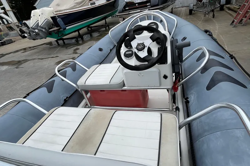 Slide: The Image of 2019 Zodiac Open 4.8 inflatable boat with steering console and seating, docked outdoors. - 5