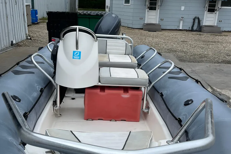 Slide: The Image of 2019 Zodiac Open 4.8 inflatable boat with seating and steering console, docked outdoors. - 6