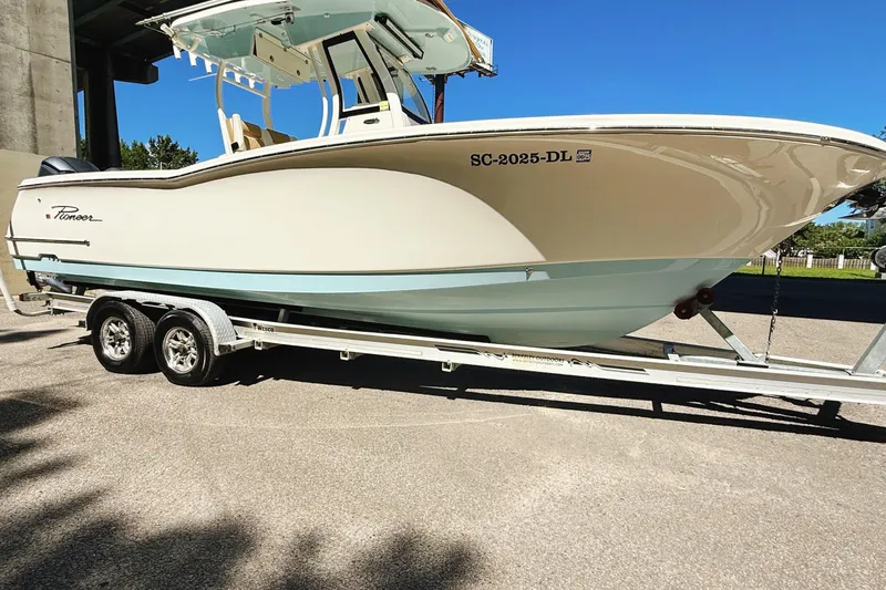 Slide: The Image of 2019 Pioneer 266 Pelagic boat on trailer, parked outdoors under clear blue sky. - 7
