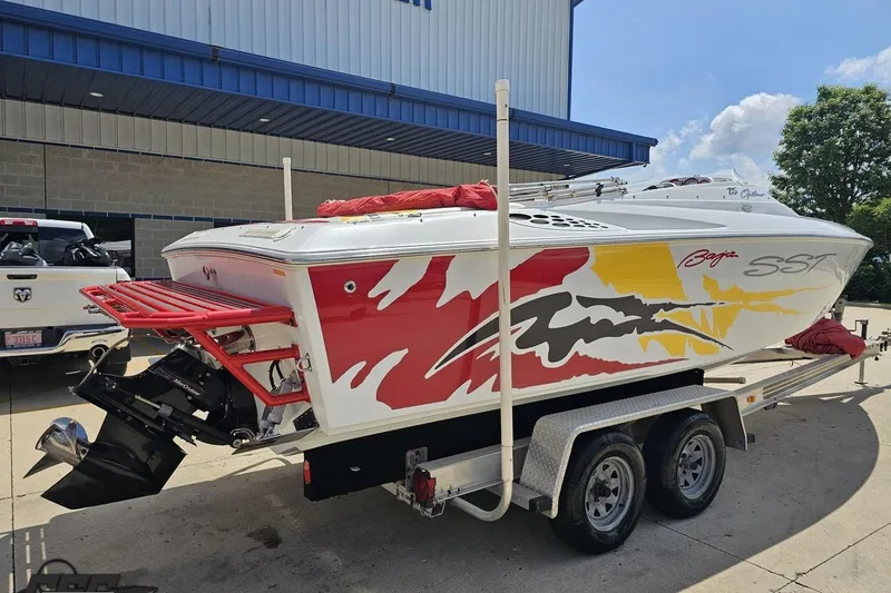 Slide: The Image of 2002 Baja 25 Outlaw speedboat on trailer with vibrant red and yellow graphics. - 11