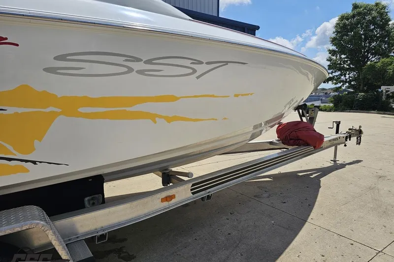 Slide: The Image of 2002 Baja 25 Outlaw boat on trailer, featuring SST graphics, parked outdoors. - 12