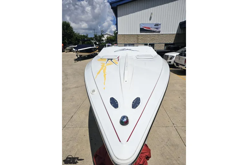 Slide: The Image of 2002 Baja 25 Outlaw speedboat with sleek design, parked outdoors under cloudy sky. - 16