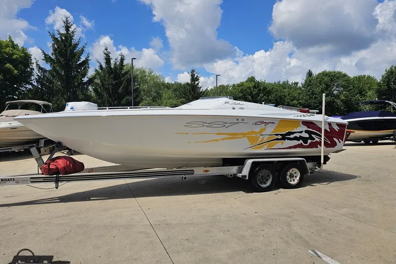 Slide: The Image of 2002 Baja 25 Outlaw boat on trailer, vibrant graphics, parked outdoors under blue sky. - 19