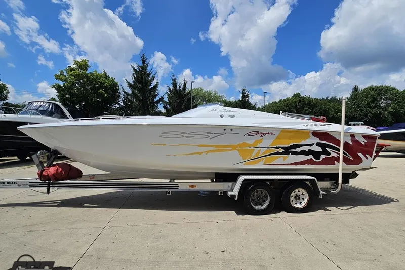 Slide: The Image of 2002 Baja 25 Outlaw speedboat on trailer, vibrant graphics, parked outdoors under blue sky. - 20