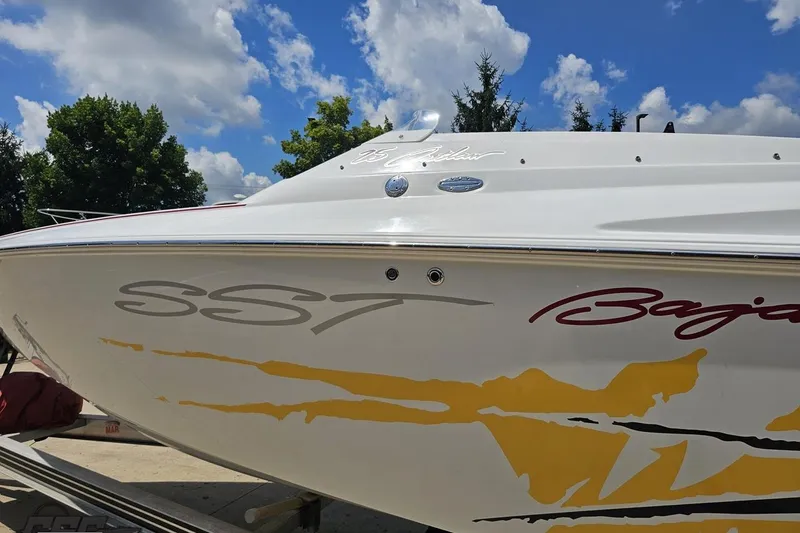 Slide: The Image of 2002 Baja 25 Outlaw boat with vibrant graphics under a blue sky. - 25