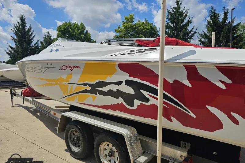 Slide: The Image of 2002 Baja 25 Outlaw boat with vibrant red and yellow graphics on a trailer. - 27