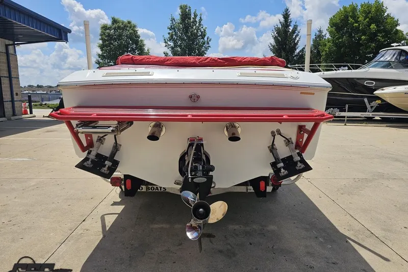 Slide: The Image of 2002 Baja 25 Outlaw boat rear view with red accents, parked outdoors. - 31