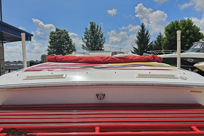 Slide: The Image of 2002 Baja 25 Outlaw boat with red accents, docked under a blue sky. - 33