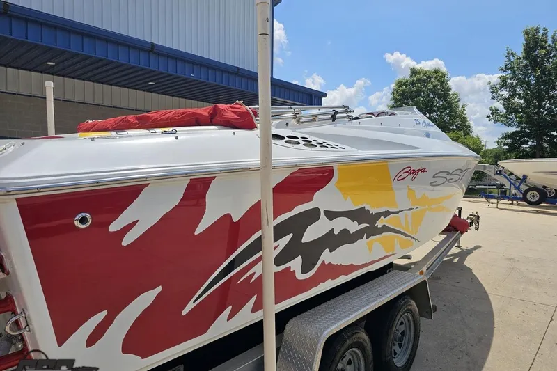 Slide: The Image of 2002 Baja 25 Outlaw boat with vibrant red and yellow graphics on a trailer. - 35