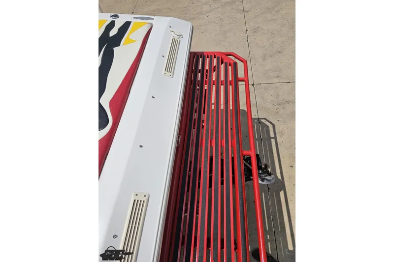 Slide: The Image of 2002 Baja 25 Outlaw boat with vibrant red and black design on trailer. - 37