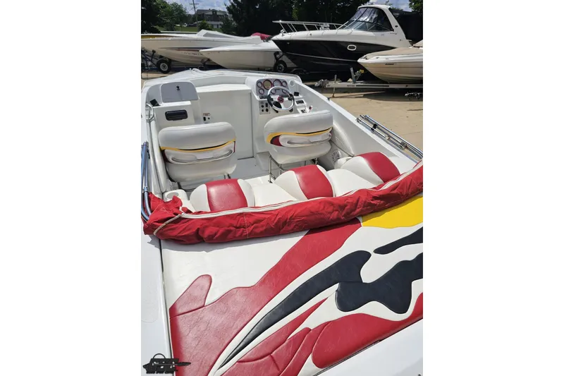 Slide: The Image of 2002 Baja 25 Outlaw boat interior with red and white seating, docked alongside other boats. - 38