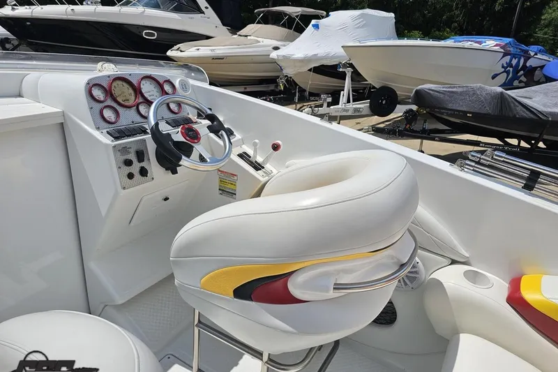 Slide: The Image of 2002 Baja 25 Outlaw boat cockpit with white and red seating, steering wheel, and gauges. - 46