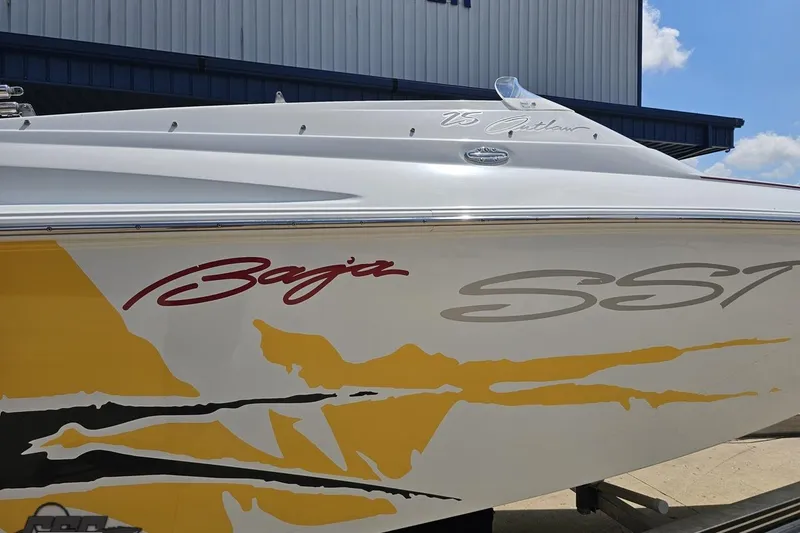 Slide: The Image of 2002 Baja 25 Outlaw boat with vibrant yellow and red graphics, docked outdoors. - 8