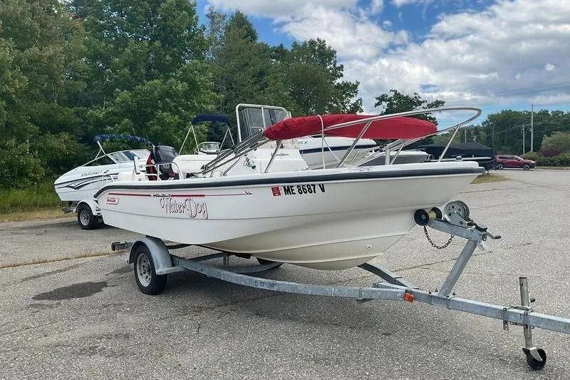 The Image of 2000 Boston Whaler 160 Dauntless boat on trailer, parked outdoors under cloudy sky. - 0