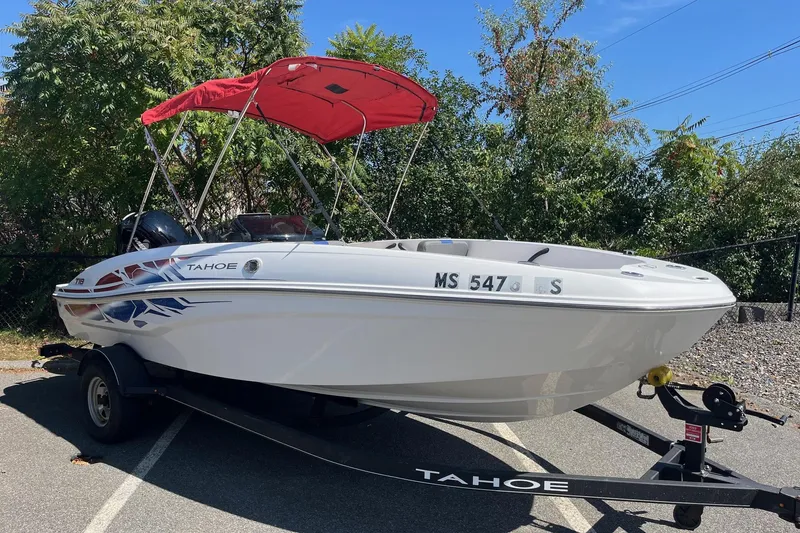 Slide: The Image of 2022 Tahoe T18 boat with red canopy on trailer, parked outdoors. - 1