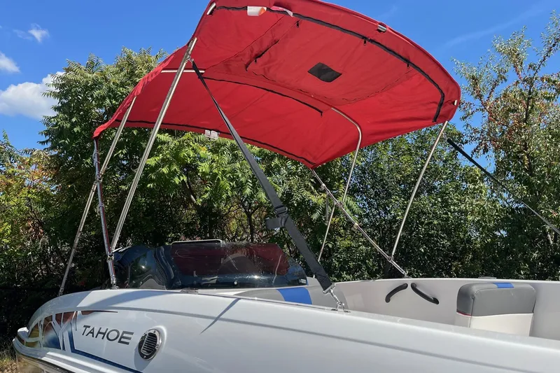 Slide: The Image of 2022 Tahoe T18 boat with red canopy, parked outdoors under blue sky. - 10