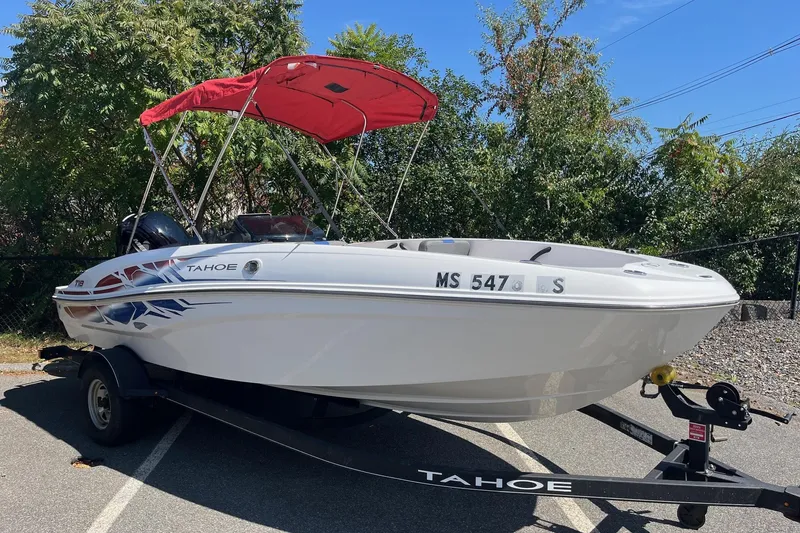 Slide: The Image of 2022 Tahoe T18 boat with red canopy on trailer, parked outdoors. - 2
