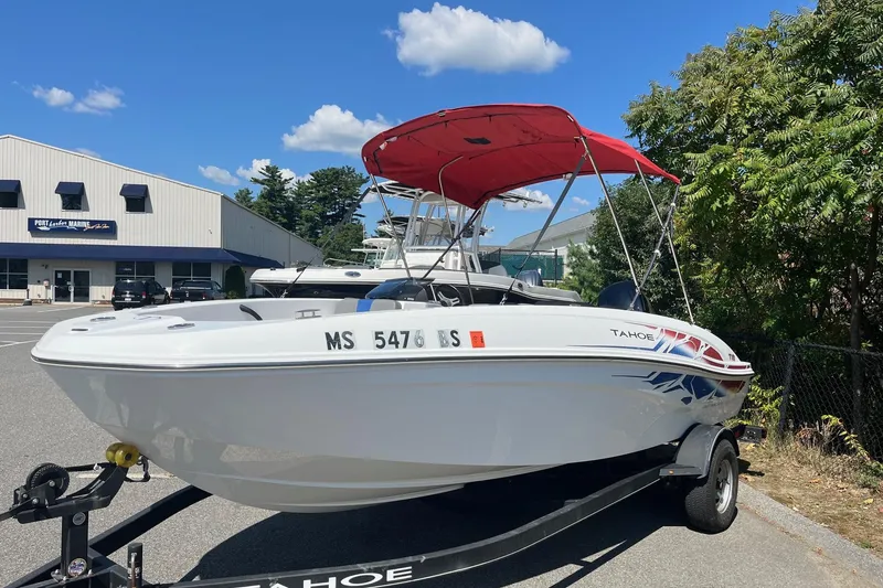Slide: The Image of 2022 Tahoe T18 boat with red canopy on trailer, parked near marine building. - 4