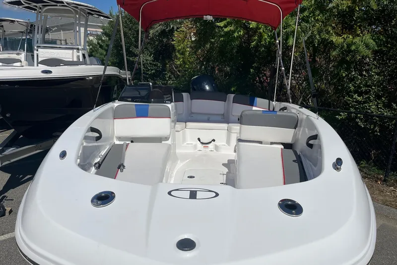 Slide: The Image of 2022 Tahoe T18 boat with red canopy, parked outdoors, showcasing spacious seating. - 9