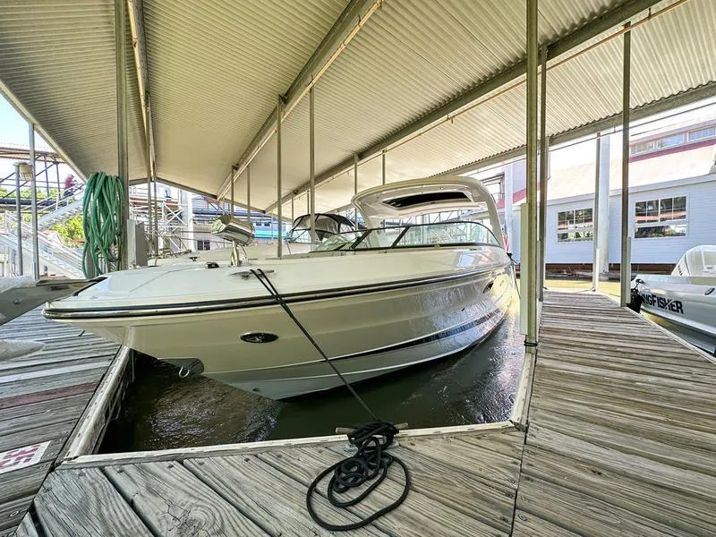 Slide: The Image of 2023 Sea Ray SLX 310 OB docked under a covered marina. - 0