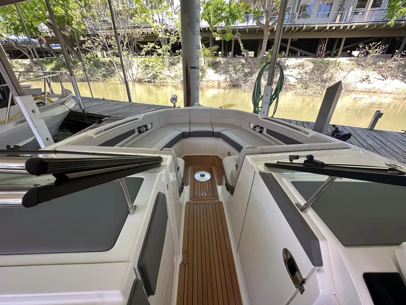 Slide: The Image of 2023 Sea Ray SLX 310 OB boat interior with teak flooring and cushioned seating. - 12