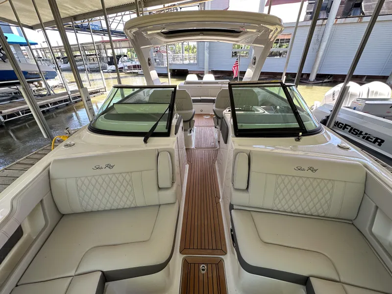 Slide: The Image of 2023 Sea Ray SLX 310 OB boat interior with white seating and wooden flooring. - 13