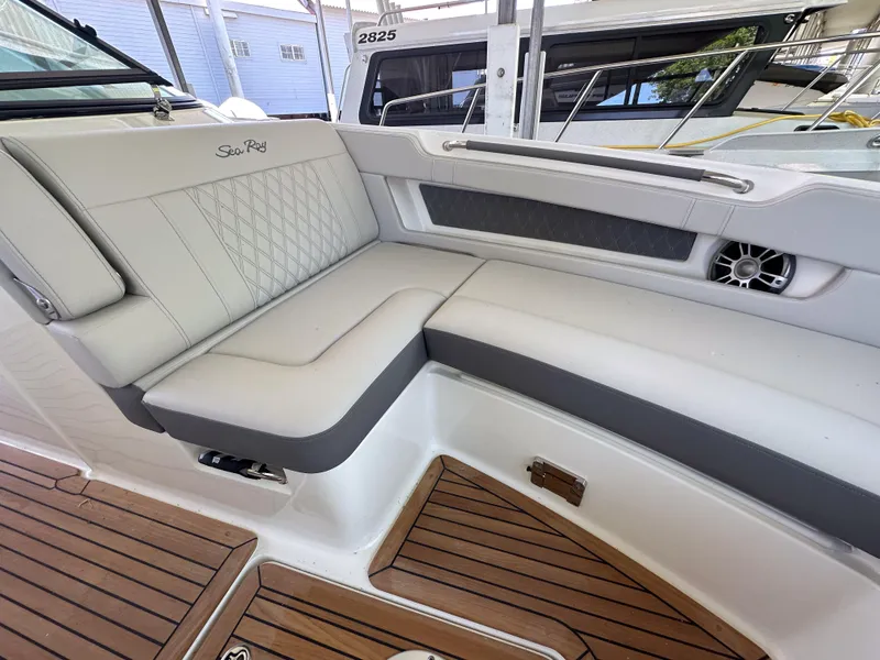 Slide: The Image of 2023 Sea Ray SLX 310 OB boat interior with cushioned seating and teak flooring. - 14