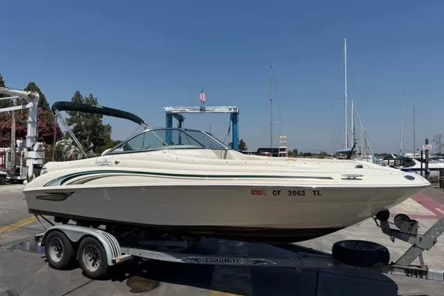 The Image of 2002 Sea Ray 210 Sundeck boat on trailer at marina, clear sky background. - 0