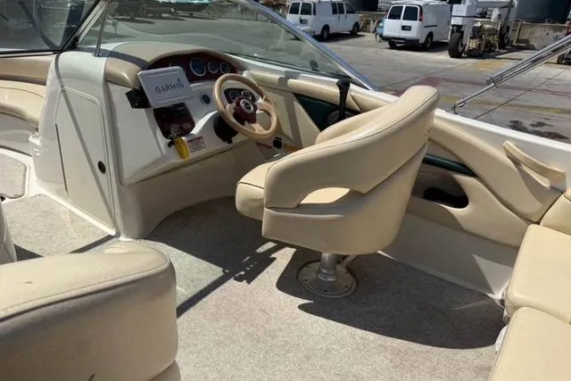 Slide: The Image of 2002 Sea Ray 210 Sundeck interior with beige seating and steering console. - 3