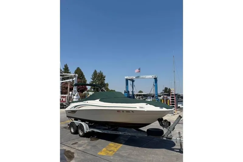 Slide: The Image of 2002 Sea Ray 210 Sundeck boat on trailer at marina, clear sky background. - 9