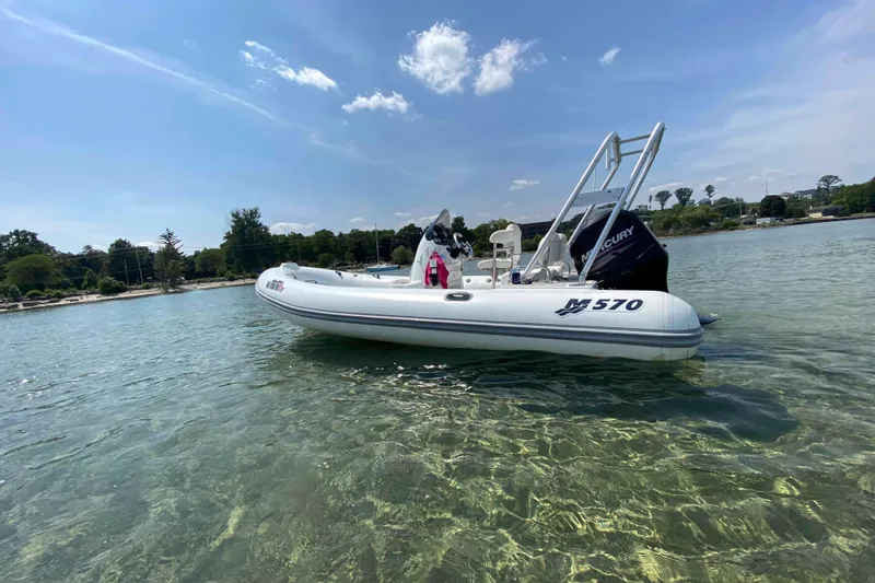 Slide: The Image of 2013 Mercury Inflatables M570 boat on clear water under blue sky. - 1