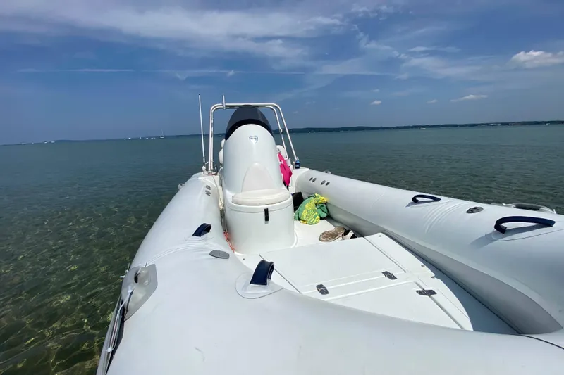 Slide: The Image of 2013 Mercury Inflatables M570 boat on calm water under clear blue sky. - 11