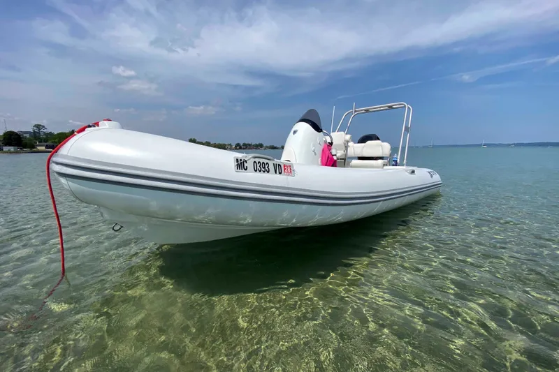 Slide: The Image of 2013 Mercury Inflatables M570 boat on clear water under blue sky. - 12
