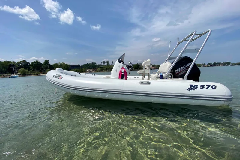 Slide: The Image of 2013 Mercury Inflatables M570 boat on clear water under blue sky. - 13