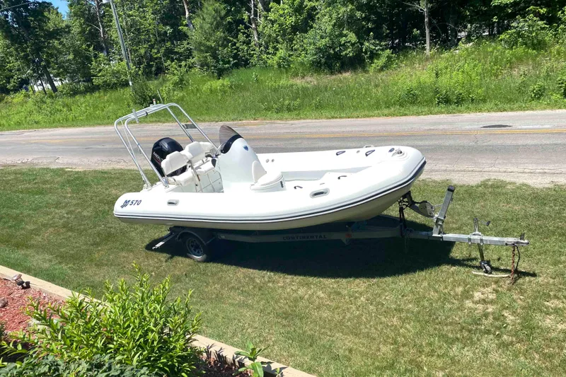 Slide: The Image of 2013 Mercury Inflatables M570 boat on trailer, parked on grass by roadside. - 3