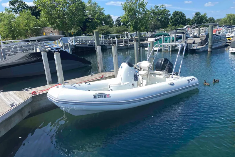 Slide: The Image of 2013 Mercury Inflatables M570 boat docked in a marina with clear blue water. - 4