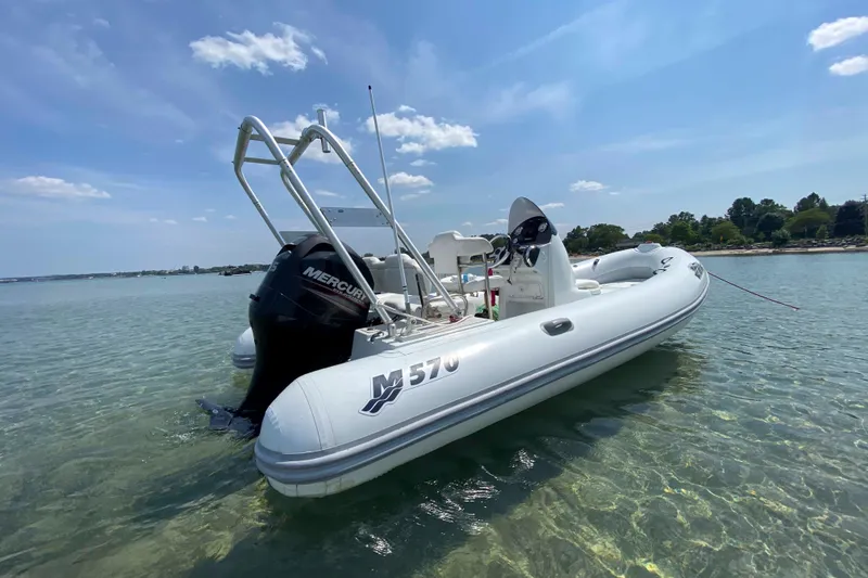 Slide: The Image of 2013 Mercury Inflatables M570 boat on clear water under blue sky. - 7