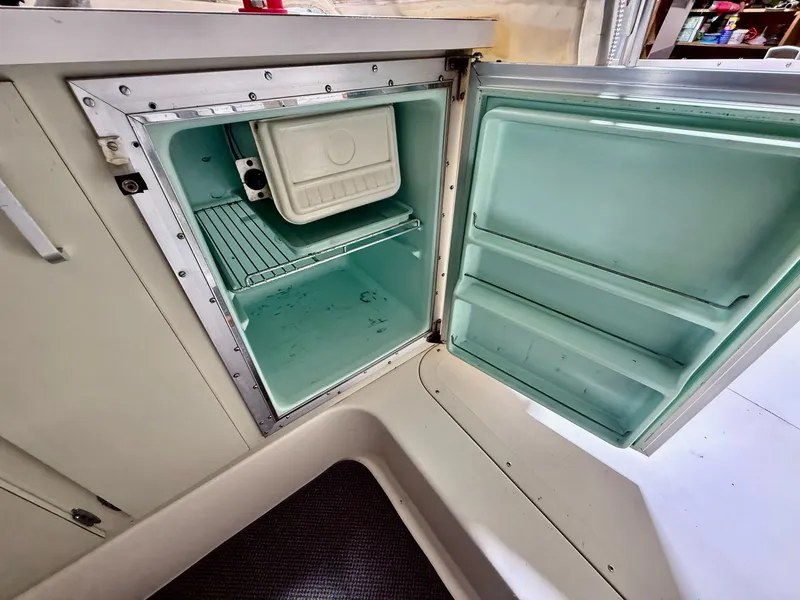 Slide: The Image of 1973 Bertram Sport Fisherman boat refrigerator with open door, showing interior shelves. - 9