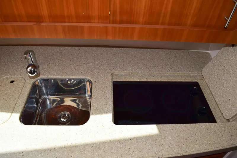 Slide: The Image of 2012 Grady-White Express 360 kitchen with sink and stovetop, featuring wood cabinetry. - 39