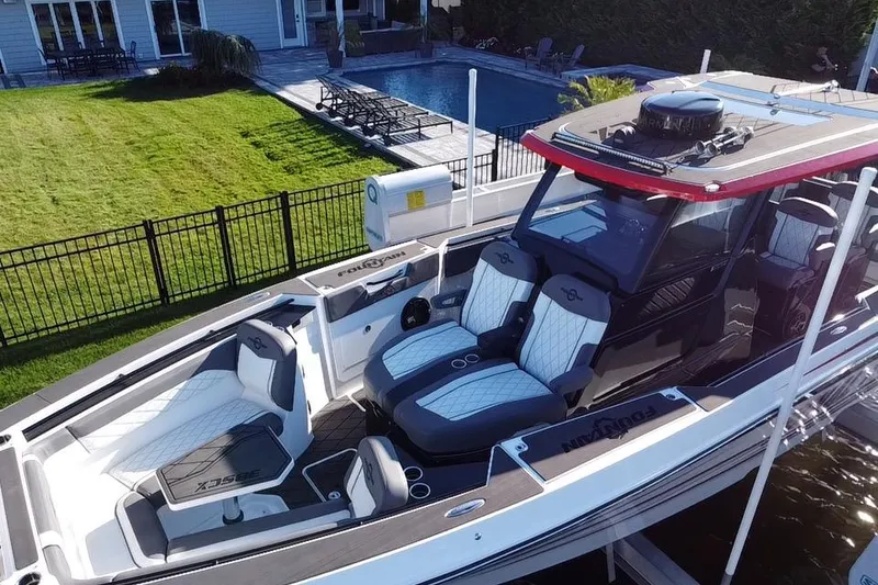 Slide: The Image of 2023 Fountain 38 SCX boat with luxurious seating and modern design, docked near a garden. - 12