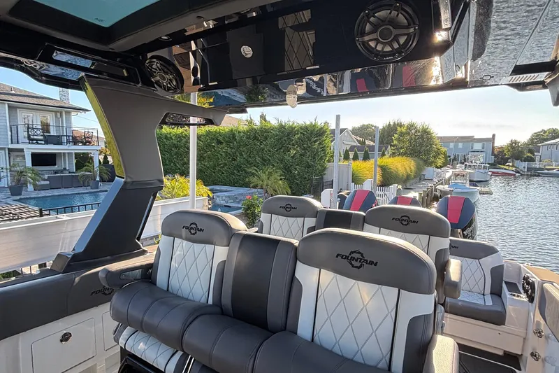 Slide: The Image of 2023 Fountain 38 SCX boat interior with seating and speakers, docked in a marina. - 35