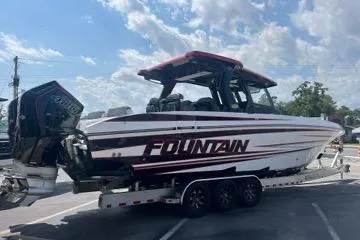 Slide: The Image of 2023 Fountain 38 SCX boat docked, covered, with lush greenery and residential backdrop. - 64