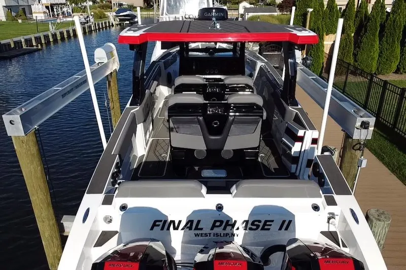 Slide: The Image of 2023 Fountain 38 SCX boat named "Final Phase" on a lift by waterfront homes. - 8